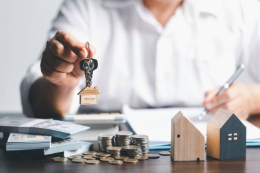 Ev satıcısında anahtarlar ve model ev müşterilere veriliyor. Emlakçı profesyonel emlakçıyla kiralık kira kontratı imzalayan müşterisi olan ev modeli..