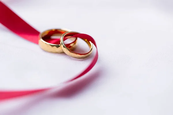 婚約指輪の黄金だ ピンクのリボンの背景と結婚黄金のリング 白と赤のバラのリング 結婚指輪はペア愛好家の伝統的な結婚式のシンボルです — ストック写真