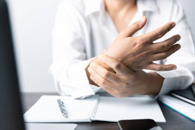 Bir ofis çalışanı dizüstü bilgisayarın önünde oturan Asyalı bir kadındır. Bir iş kadını ellerini ve parmaklarını strese sokuyor. Bir kadın ofis müdürü iş yerinde çok yoruldu..