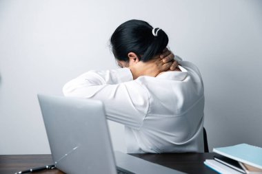 Bir ofis çalışanı dizüstü bilgisayarın önünde oturan Asyalı bir kadındır. Bir iş kadını ellerini ve parmaklarını strese sokuyor. Bir kadın ofis müdürü iş yerinde çok yoruldu..