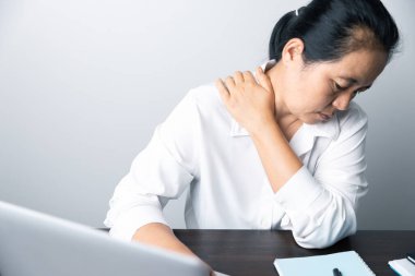Bir ofis çalışanı dizüstü bilgisayarın önünde oturan Asyalı bir kadındır. Bir iş kadını ellerini ve parmaklarını strese sokuyor. Bir kadın ofis müdürü iş yerinde çok yoruldu..