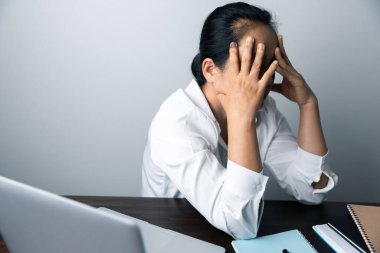 Bir ofis çalışanı dizüstü bilgisayarın önünde oturan Asyalı bir kadındır. Bir iş kadını ellerini ve parmaklarını strese sokuyor. Bir kadın ofis müdürü iş yerinde çok yoruldu..