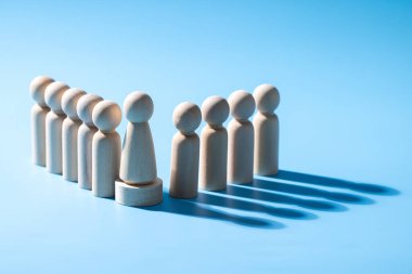 Ahşap bir takım çalışması sembolü. Liderlik stili strateji işbirliği kavramı. Şirketten bir grup çalışan. Açık mavi arkaplanı olan ahşap sembol. Profesyonel iş grubu.