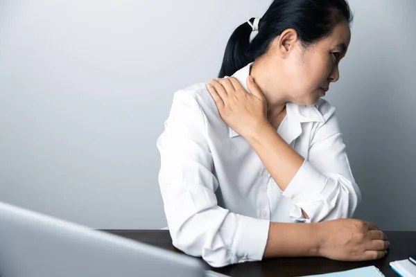 stock image A business office worker is an asian woman is sitting in front of the laptop computer. A businesswoman stressing her body part fingers, hands arm. A femaleOffice manager is exhausted at her workplace.