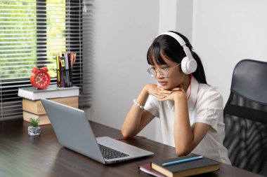 Öğrenci kız çevrimiçi çalışmaktan mutlu, okul konseptine geri dönüyor. Çalışmakla meşgul genç bir kız öğrenci not defterine not alır ve bilgisayarla çevrimiçi eğitim teknolojisi eğitimi verir..