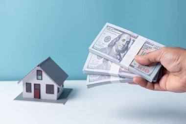 Beyaz Saray model geçmişi olan bir kadının elinde dolar banknotu var. Konut kredisi onaylı ev kredisi ve sigorta kavramı.