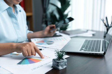 İş kadınları şirket mali istatistiklerini, beyin fırtınası fikirlerini ve masadaki grafik dokümanlarını incelemek için birlikte çalışıyorlar..