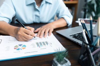 İş kadınları şirket mali istatistiklerini, beyin fırtınası fikirlerini ve masadaki grafik dokümanlarını incelemek için birlikte çalışıyorlar..