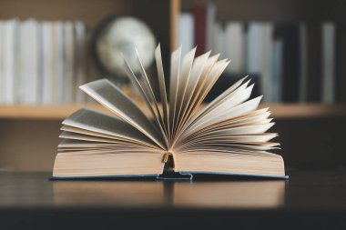 Eğitim öğrenme konsepti. Eski açık ders kitabıyla kütüphanede kitap, okuma masasında edebiyat metin arşivi yığını, akademik arkaplanı için okul çalışma odası arka planında kitaplıkların koridoru.