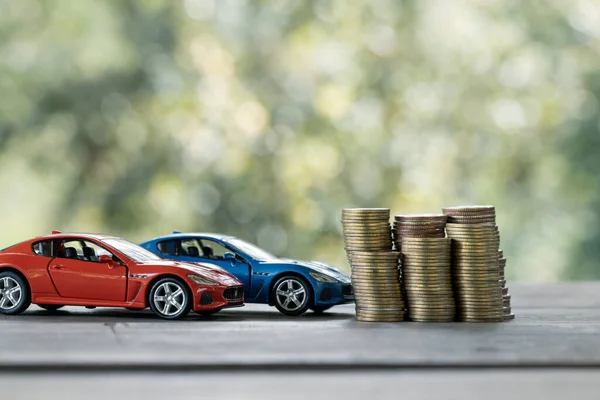 Saving money for car, Finance and car loan, Investment and business concept. Miniature car model with growing stack of coins money on nature green background.