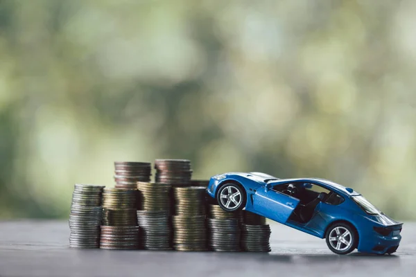 Saving money for car, Finance and car loan, Investment and business concept. Miniature car model with growing stack of coins money on nature green background.