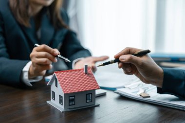 Genç bir kadın bir bankerle ev kredisi için buluşuyor, emlak konsepti. Onaylanmış mortgage başvuru formu, ipotek kredisi teklifi ve konut sigortası hakkında.