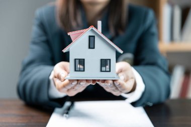 Ellerinde küçük bir oyuncak ev, modern evi barındıran kadınların ellerini kapat, sigorta ya da kredi al ya da gayrimenkul ya da mülk al. Onaylanmış mortgage başvuru formu, ipotek kredisi teklifiyle ilgili.