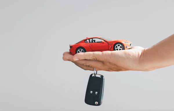 Hand holding car keys and a remote control for keyless entry. Car loan, contract agreement, buying and rent car concept, Sale person holding car key on hand.