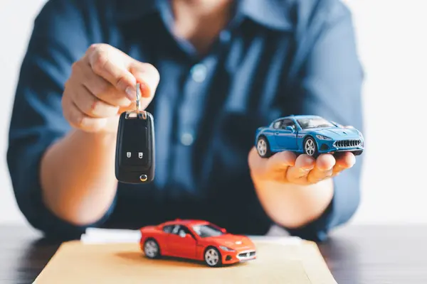 Hand holding car keys and a remote control for keyless entry. Car loan, contract agreement, buying and rent car concept, Sale person holding car key on hand.