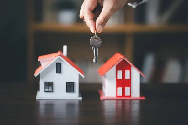 House key in hand, Key with model home on wooden table, Save money concept, Property investment, house loan, reverse mortgage, gold coins money stack growth, saving money coins stack future for home