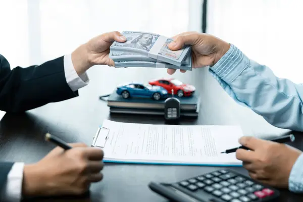 Closeup hand giving money for loan credit financial, lease and rental concept. Car dealers and protect against damage and risk of driving.