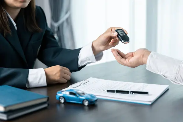 Closeup hand giving a car key and money for loan credit financial, lease and rental concept. Car dealers or insurance managers cover and protect against damage and the risk of driving, Hold car keys.