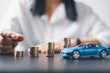 Araba sigortası işi, tasarruf satışı, yeni araba için vergi ve kredi. Arka planda bozuk para yığını olan oyuncak araba. Ulaşım finansmanını yönetmeyi planlıyorum. Araba için kredi