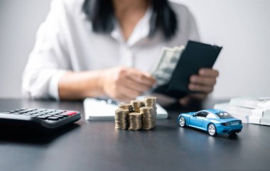 Araba sigortası işi, tasarruf satışı, yeni araba için vergi ve kredi. Arka planda bozuk para yığını olan oyuncak araba. Ulaşım finansmanını yönetmeyi planlıyorum. Araba için kredi