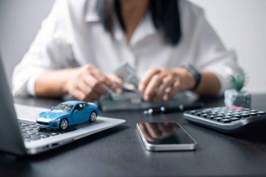 Araba sigortası işi, tasarruf satışı, yeni araba için vergi ve kredi. Arka planda bozuk para yığını olan oyuncak araba. Ulaşım finansmanını yönetmeyi planlıyorum. Araba için kredi