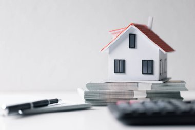 Paralı ev. Finans kavramı ya da gayrimenkul yeniden finanse etme. Evin sembolü dolarlarımızın arka planında duruyor. Emlak yatırımı. Ev kredisi oranı. Emeklilik için para biriktiriyorum.