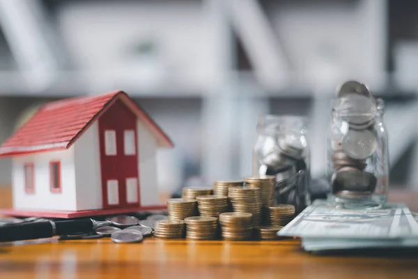 House model and money coins saving for concept saving money for buying a house, investment mortgage finance, and home loan refinance financial plan home. Property insurance and tax money.