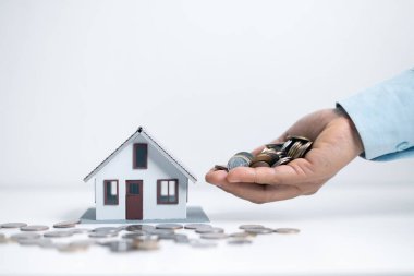İş kadını, madeni para yığınına para ve ahşap masa üzerine de model ev koydu. Ev almak için para biriktiriyorum, ev kredisi için finansal planlar yapıyorum. Küçük ev, ev veya konsept satın almak için para biriktirme.