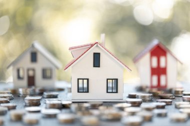 Ev modeli ve madeni paralar ahşap masanın üzerinde. Ev için para biriktirme kavramı, emlak ipoteği, inşaat yatırımı, emlak faizi, banka kredisi, sigorta işi, finans, muhasebe