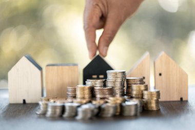 Ev modeli ve madeni paralar ahşap masanın üzerinde. Ev için para biriktirme kavramı, emlak ipoteği, inşaat yatırımı, emlak faizi, banka kredisi, sigorta işi, finans, muhasebe