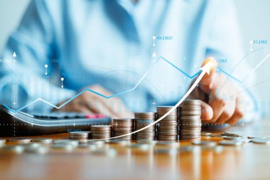 Finansal iş büyümesi kavramı. İş adamı yatırımlardaki gelir ve karı ve hisse senedi grafiğiyle olumlu büyüme göstergelerinde bir artış hesaplıyor. Zengin, madeni para