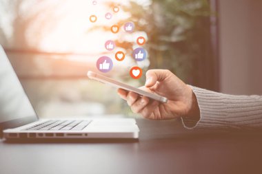 Sosyal medya ve dijital online konsept. Cep telefonunda sosyal medya pazarlaması yapan kişi, bildirim simgeleriyle akıllı telefon ekranının üzerinde mesaj, yorum ve yıldız kullanıyor. Telefon Sosyal medyası.