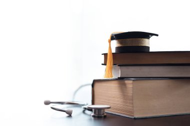 Tıbbi kitaplarla çevrili ve steteskopla donatılmış, yıllarca süren eğitim ve kaliteli sağlık hizmetlerine adanmışlığın somutlaştırılmış hali. Tıp eğitimi kavramı. Doktor, ilaç..