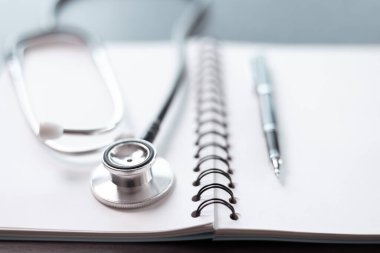 Tıbbi kitaplarla çevrili ve steteskopla donatılmış, yıllarca süren eğitim ve kaliteli sağlık hizmetlerine adanmışlığın somutlaştırılmış hali. Tıp eğitimi kavramı. Doktor, ilaç..