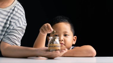 Genç çocuk finans okuyarak, madeni para biriktirerek ve yatırımın ve çocuklar için biriktirmenin önemini anlayarak para biriktirmeyi öğreniyor. çocuk, para biriktirme, öğrenim, çocuklar, kişi, para, finans.