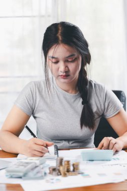 Genç Asyalı kadın yığınla para kazanıyor. Yatırım tasarruf konsepti, tasarruf, yatırım. Masada yığınla bozuk para ve banka hesap makinesi, tasarruf etmek için para ve gelir elde etmek için yatırım..