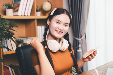 Asyalı kız ev ödevi yapıyor ve evde çalışıyor. Masa başında dizüstü bilgisayar kullanan bir kadın webinar izleyen, online çalışan, internet dersine giren ya da evden kumandalı sanal telefon görüşmesi yapan notlar yazıyor..