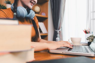 Kadın dizüstü bilgisayarda çalışıyor, not defterine not alıyor, internetten ders çalışıyor, Webinar izliyor, bilgisayar kullanıyor, kontrol listesi yazıyor. Uzaktan eğitim, e öğrenme konsepti.