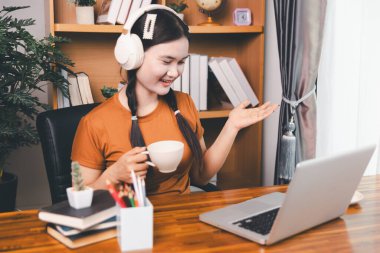 Asyalı kız ev ödevi yapıyor ve evde çalışıyor. Masa başında dizüstü bilgisayar kullanan bir kadın webinar izleyen, online çalışan, internet dersine giren ya da evden kumandalı sanal telefon görüşmesi yapan notlar yazıyor..