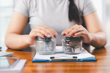 Genç Asyalı kadın yığınla para kazanıyor. Yatırım tasarruf konsepti, tasarruf, yatırım. Masada yığınla bozuk para ve banka hesap makinesi, tasarruf etmek için para ve gelir elde etmek için yatırım..