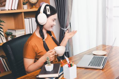 Asyalı kız ev ödevi yapıyor ve evde çalışıyor. Masa başında dizüstü bilgisayar kullanan bir kadın webinar izleyen, online çalışan, internet dersine giren ya da evden kumandalı sanal telefon görüşmesi yapan notlar yazıyor..