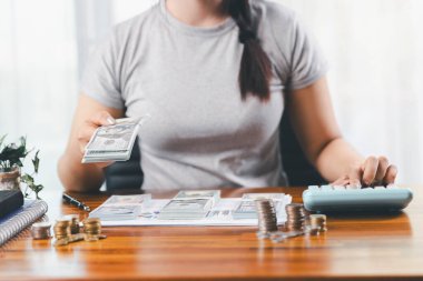 Genç Asyalı kadın yığınla para kazanıyor. Yatırım tasarruf konsepti, tasarruf, yatırım. Masada yığınla bozuk para ve banka hesap makinesi, tasarruf etmek için para ve gelir elde etmek için yatırım..