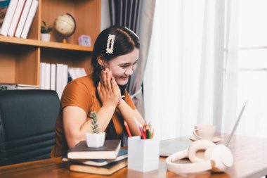 Asyalı kız ev ödevi yapıyor ve evde çalışıyor. Masa başında dizüstü bilgisayar kullanan bir kadın webinar izleyen, online çalışan, internet dersine giren ya da evden kumandalı sanal telefon görüşmesi yapan notlar yazıyor..