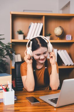 Asyalı kız ev ödevi yapıyor ve evde çalışıyor. Masa başında dizüstü bilgisayar kullanan bir kadın webinar izleyen, online çalışan, internet dersine giren ya da evden kumandalı sanal telefon görüşmesi yapan notlar yazıyor..