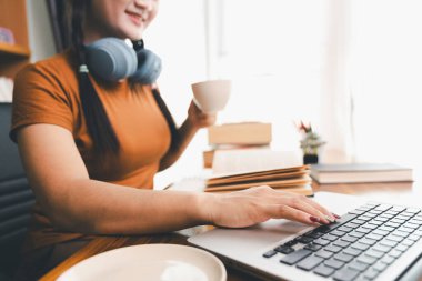 Kadın dizüstü bilgisayarda çalışıyor, not defterine not alıyor, internetten ders çalışıyor, Webinar izliyor, bilgisayar kullanıyor, kontrol listesi yazıyor. Uzaktan eğitim, e öğrenme konsepti.