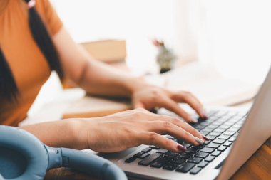 Kadın dizüstü bilgisayarda çalışıyor, not defterine not alıyor, internetten ders çalışıyor, Webinar izliyor, bilgisayar kullanıyor, kontrol listesi yazıyor. Uzaktan eğitim, e öğrenme konsepti.