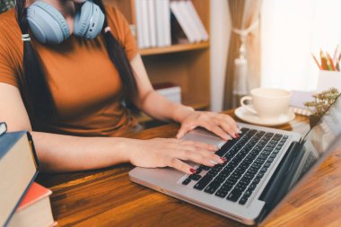 Kadın dizüstü bilgisayarda çalışıyor, not defterine not alıyor, internetten ders çalışıyor, Webinar izliyor, bilgisayar kullanıyor, kontrol listesi yazıyor. Uzaktan eğitim, e öğrenme konsepti.