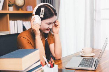 Asyalı kız ev ödevi yapıyor ve evde çalışıyor. Masa başında dizüstü bilgisayar kullanan bir kadın webinar izleyen, online çalışan, internet dersine giren ya da evden kumandalı sanal telefon görüşmesi yapan notlar yazıyor..