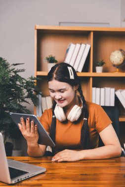 Uzak bir toplantıyla Asyalı ev okulu öğrencisi okul öğretmeninden sanal internet dersini öğreniyor. Kadın kulaklıkla matematik öğretiyor. Eğitim konsepti. Okulda bilgisayar eğitimi alan bir öğrenci.