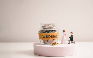 Düğün ve düğün planlama için para biriktir. Aile hayatı ya da evlilik hayatı için sürdürülebilir finansal amaç. Yükselen madeni paralar üzerinde minyatür düğün, yeni aile için tasarruf veya büyümeyi resmediyor.